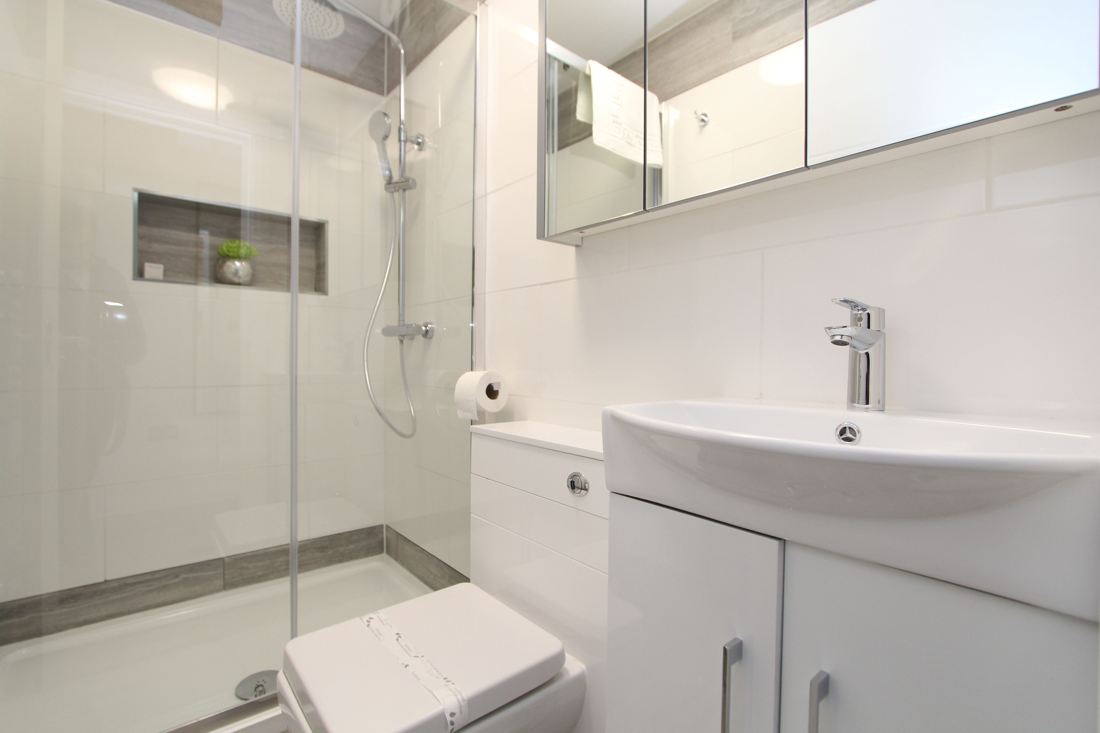 Ein modernes Badezimmer mit Duschkabine aus Glas, einem weißen Waschbecken und einer Toilette.