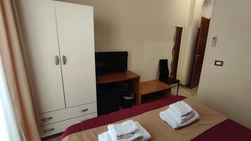 A hotel room with a bed, a desk, a wardrobe, a chair, and a TV.