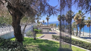 A coastal promenade with a metal fence, a small kiosk, and a view of the sea and mountains. - Abacus (Reggio Calabria)