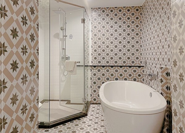 A bathroom with a glass-enclosed shower, a freestanding bathtub, and patterned tiles on the walls. - Chezzotel Pattaya (Pattaya)