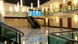 Un moderno vestíbulo de hotel con una escalera central, barandillas de vidrio y un suelo pulido.