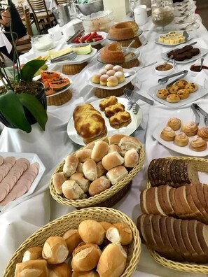 A buffet table with various food items including bread, pastries, and sliced meats. - Itu Plaza Hotel (Itu)