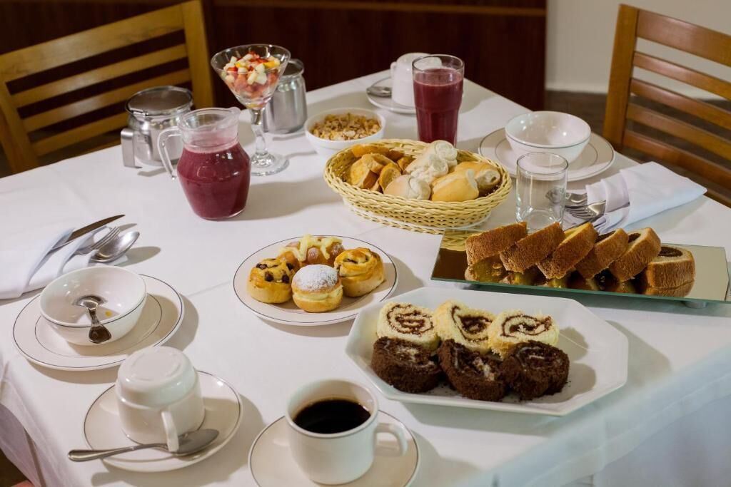 A breakfast table with various pastries, a pitcher of juice, and a basket of bread.