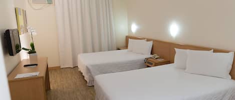 Habitación de hotel con dos camas, un escritorio, un teléfono y aire acondicionado instalado en la pared.