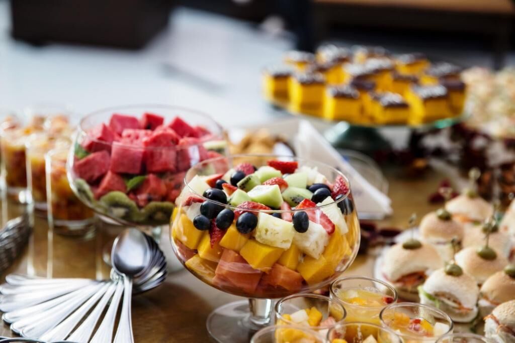 A buffet with various dishes including fruit parfaits and sandwiches.