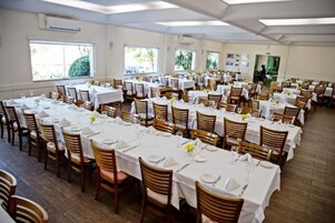 A large dining hall with multiple tables set for dining, arranged in rows.