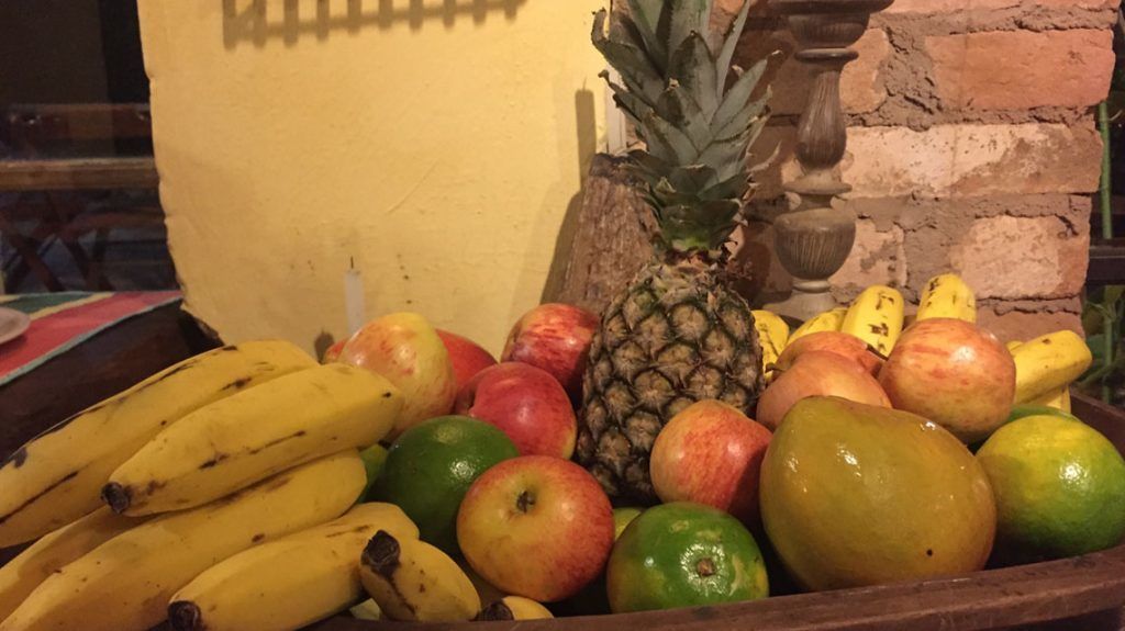 A fruit display with bananas, apples, pineapples, and limes.