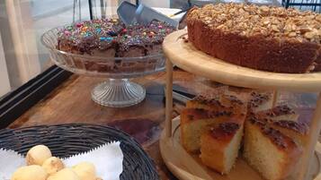 Un tavolo del buffet con diverse preparazioni da forno, tra cui torte, pane e dolci.