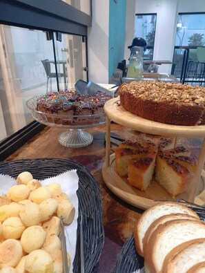 Una mesa de buffet con diversas opciones de repostería, como pasteles, pan y bollos.