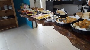 A buffet setup with various food items and utensils on a wooden counter. - Flor Inn Praia Hotel (Florianópolis)