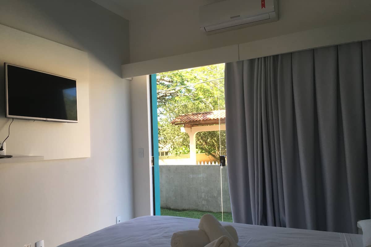 Ein Hotelzimmer mit Bett, Flachbildfernseher an der Wand und einem Fenster mit Vorhängen.