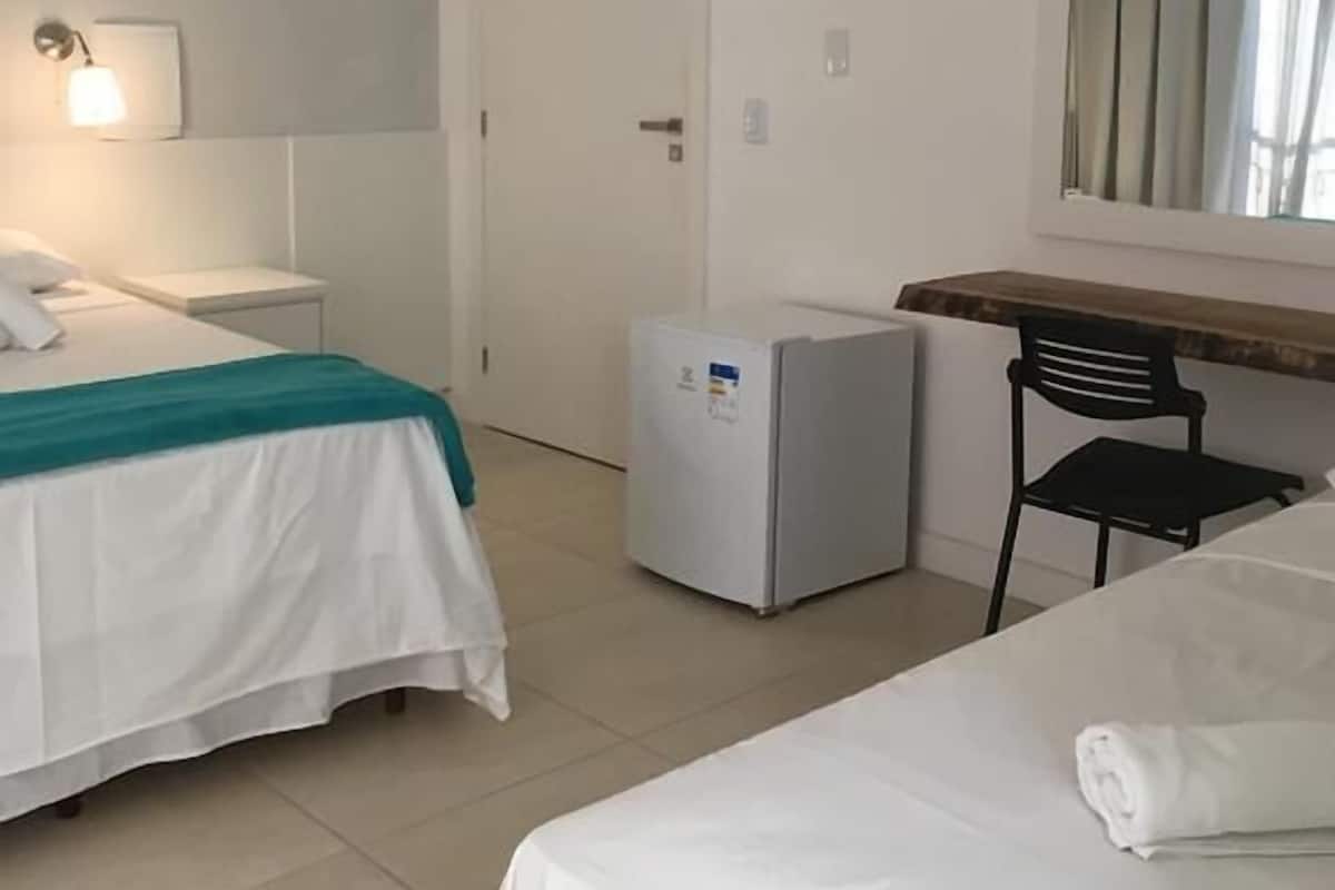 Ein Hotelzimmer mit einem Bett, einem Schreibtisch, einem Stuhl, einem Kühlschrank und einer Tür.