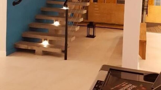 A modern staircase with wooden steps and black handrails, leading to a lower level. - Flor Inn Praia Hotel (Florianópolis)
