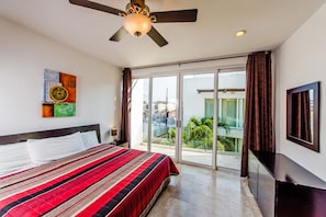 A hotel room with a large bed, a ceiling fan, a sliding glass door to a balcony, and a TV mounted on the wall. - Mamitas Village PH301 by PRP (Playa del Carmen)
