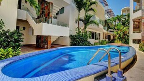 A modern hotel with a swimming pool, outdoor terraces, and lush greenery.