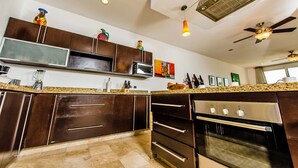 A modern kitchen with dark wooden cabinets, stainless steel appliances, and a granite countertop.