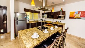 A modern kitchen with granite countertops, stainless steel appliances, and a central island with seating.