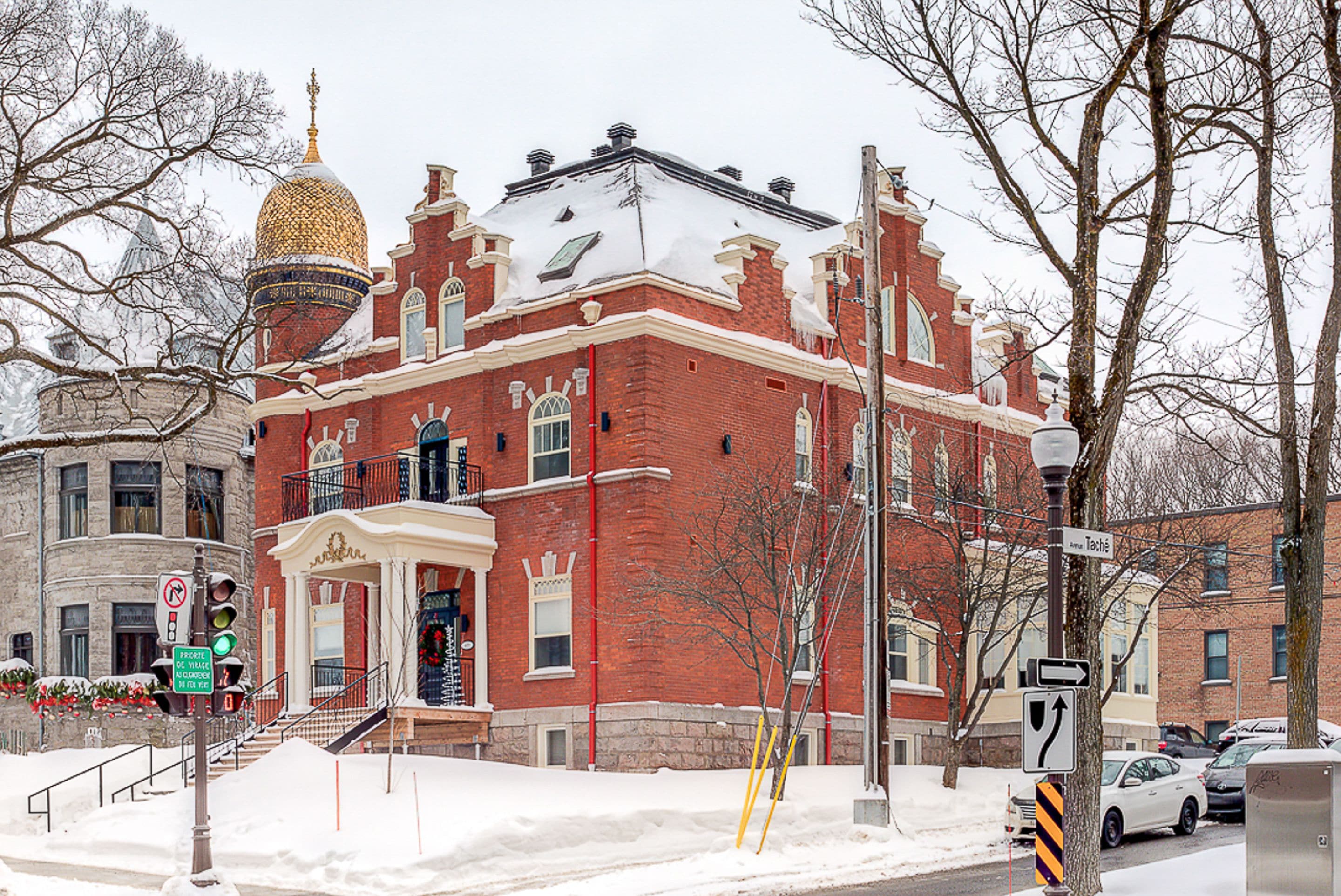 A historic building with a red brick facade, a golden dome, and a white entrance with steps.
