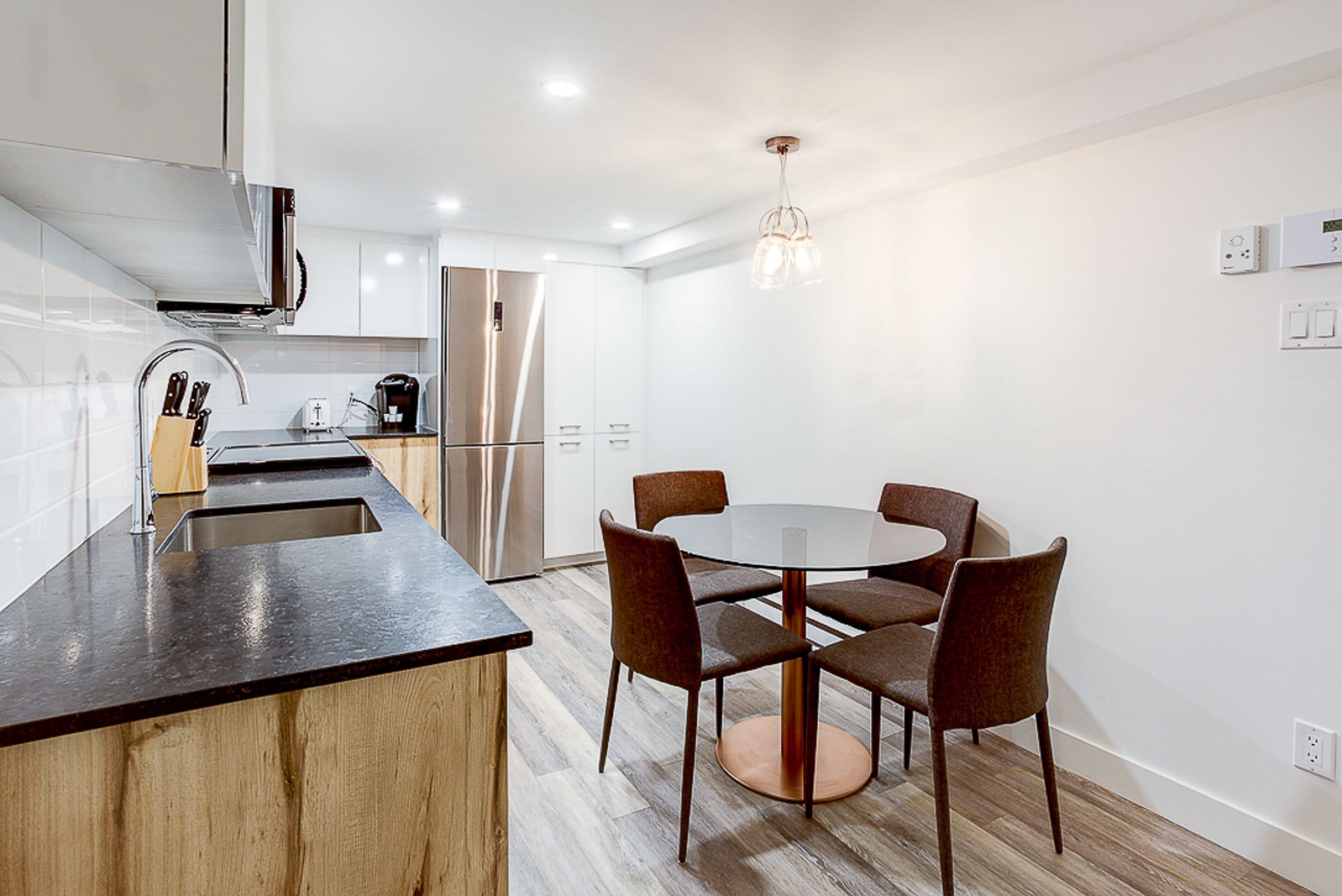 A modern kitchen with a central island, stainless steel appliances, and a round dining table with chairs.