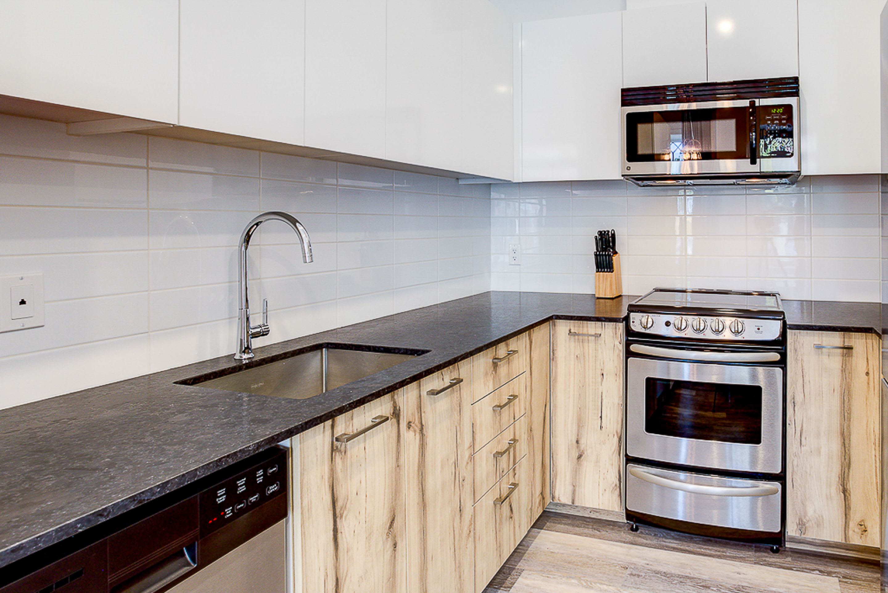 A modern kitchen with a dishwasher, stainless steel oven, and a microwave.