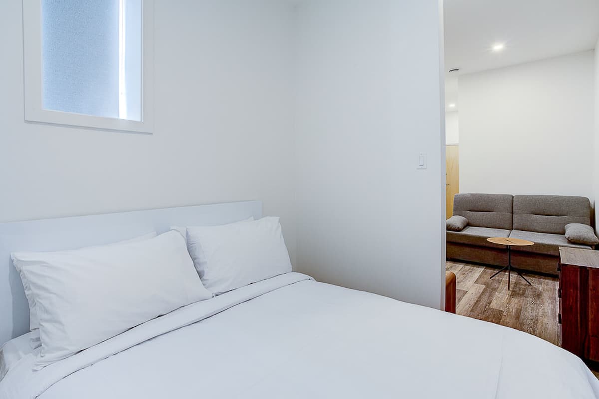 Une chambre à coucher avec un lit, une fenêtre et un canapé dans la pièce adjacente.