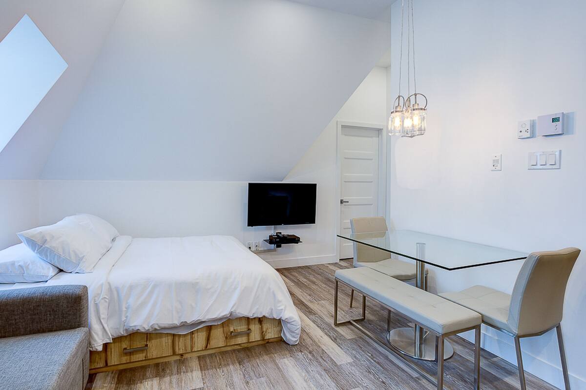 Une chambre à coucher moderne avec un lit, une télévision, un bureau et une chaise.