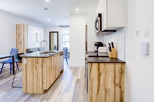 Una cocina moderna con armarios de madera, una isla central y una zona de comedor con sillas azules.