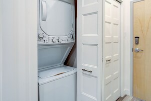 Un lavadero con lavadora y secadora, una puerta blanca y una puerta de madera.