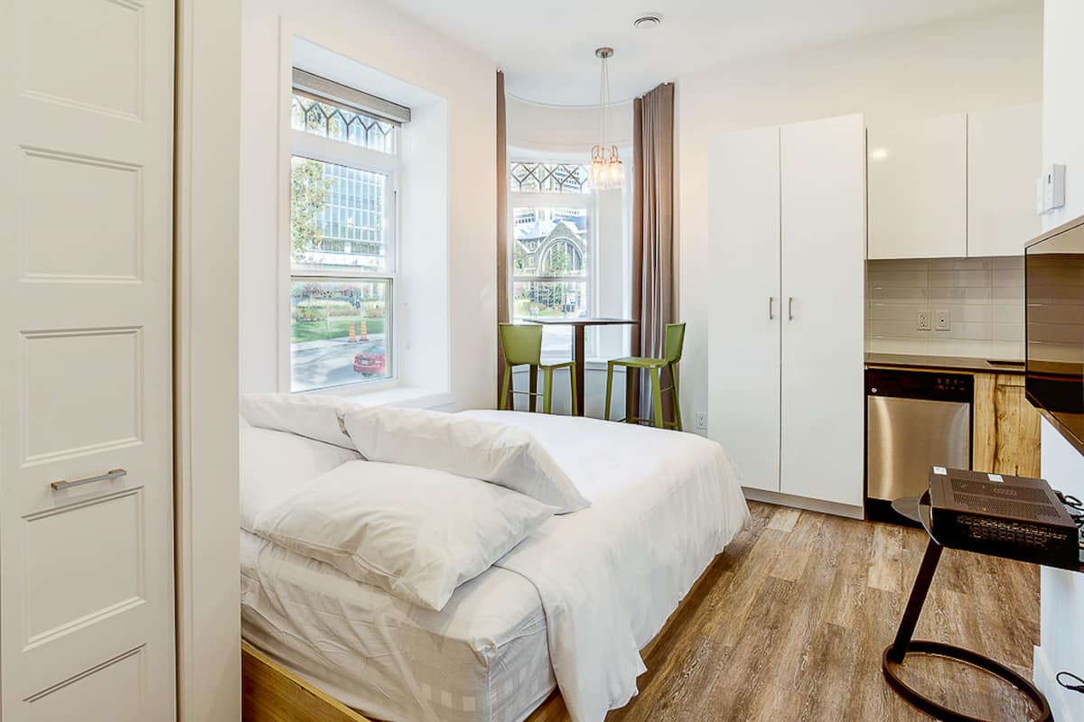 Une chambre d’hôtel de taille réduite, comprenant un lit, une petite table à manger et un coin cuisine.
