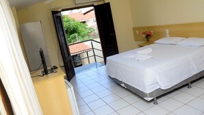 A hotel room with a bed, a desk, a chair, a window, and a balcony. - Hotel Sambaquis (São Luís)