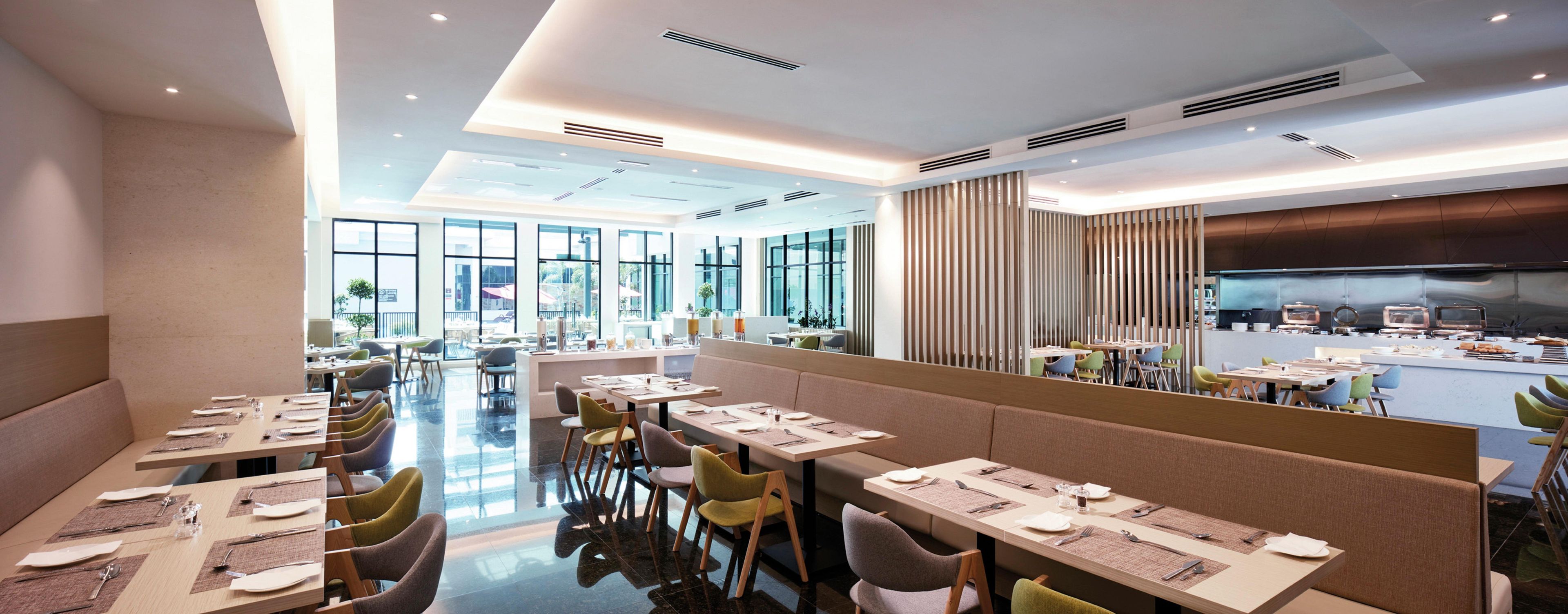 A modern restaurant with high ceilings, large windows, and a central bar area.