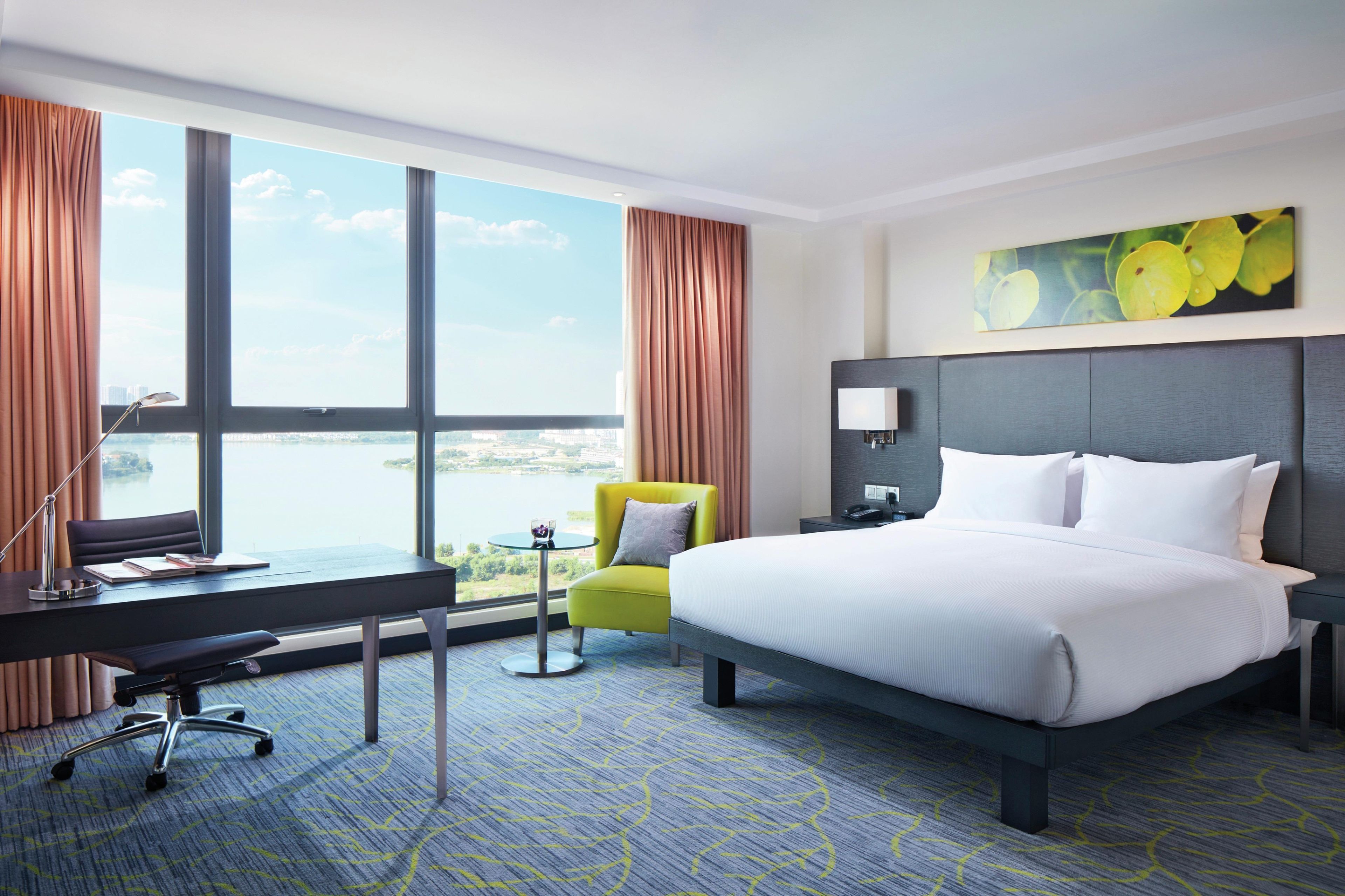 Una habitación de hotel con una cama grande, un escritorio, una silla y vistas a la ciudad.