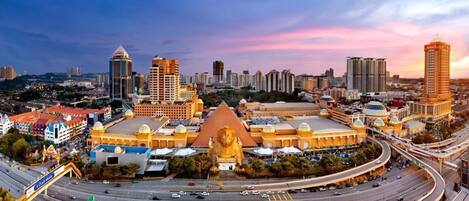 Un edificio grande y moderno con una llamativa estatua dorada de león en primer plano, rodeado de rascacielos y calles transitadas.