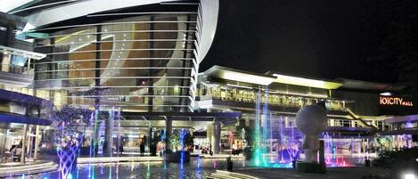 Un bâtiment moderne à la façade incurvée, agrémenté d’un élément décoratif aquatique à l’avant.