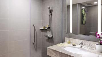 Un baño moderno con cabina de ducha, un espejo grande y un lavamanos de mármol.