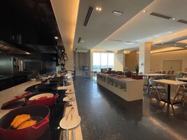 A modern kitchen with a long counter, cooking utensils, and a view of the city.