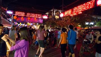 Una calle concurrida con letreros de neón que indican 'PUB STREET' y 'PUB STREET', señal de una zona de vida nocturna.