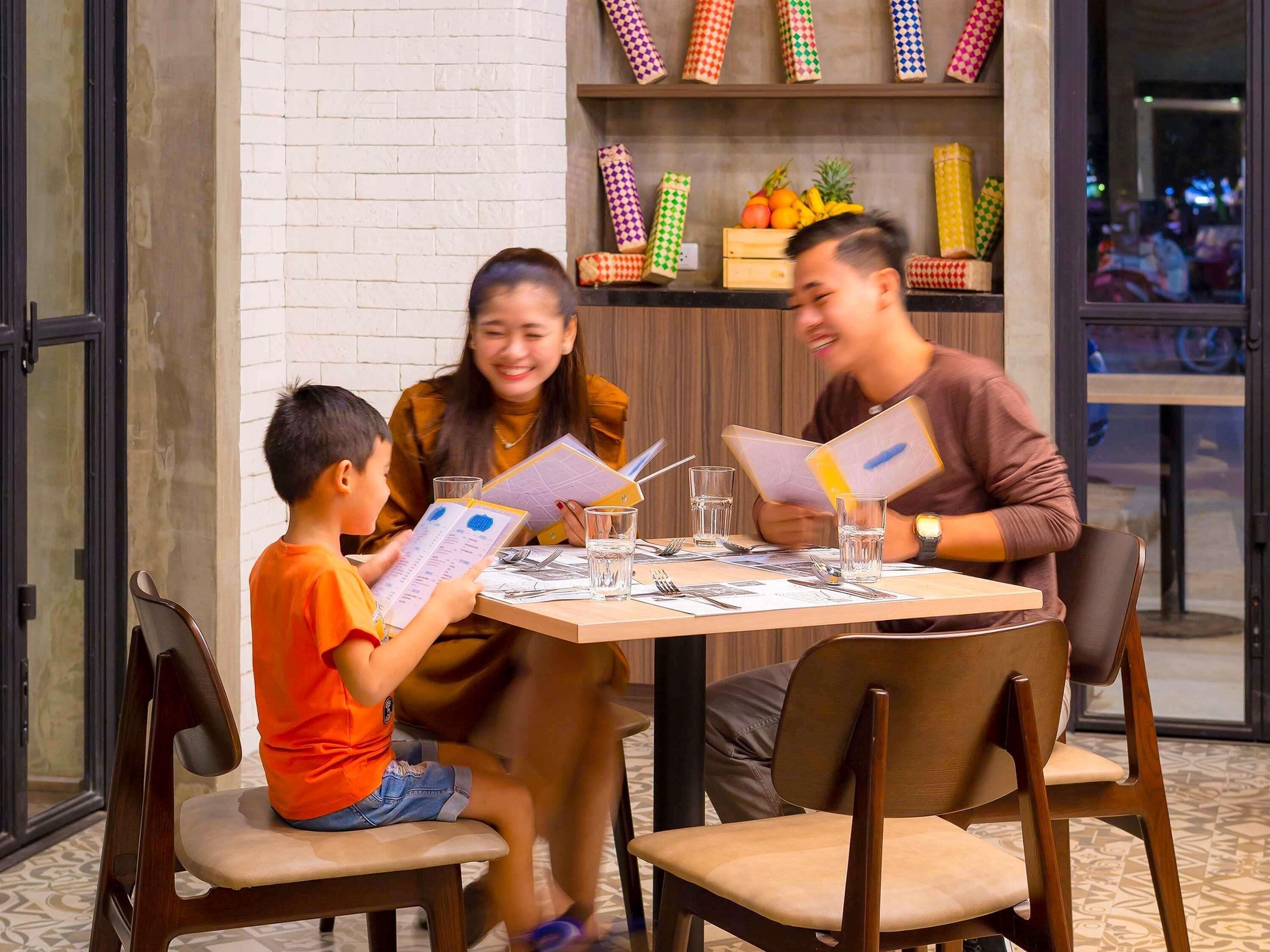 A family dining at a restaurant with a brick wall and a shelf with colorful napkins.