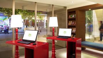 A hotel reception area with two red desks, each with a laptop and a lamp.