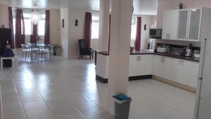 A spacious living area with a dining table, chairs, a sofa, and a kitchen area with cabinets and appliances. - Campeche Villa (Mero)