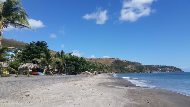 A beach with a clear sky, palm trees, and a hilly landscape in the background. - Campeche Villa (Mero)