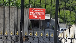 A gated entrance with a 'Welcome to CAMPECHE VILLA' sign, surrounded by lush greenery and a clear sky. - Campeche Villa (Mero)