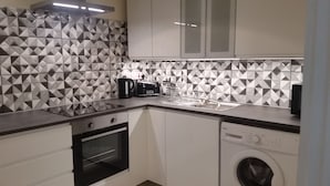 A compact kitchen with a modern geometric backsplash, a built-in oven, a dishwasher, and a coffee maker. - Campeche Villa (Mero)