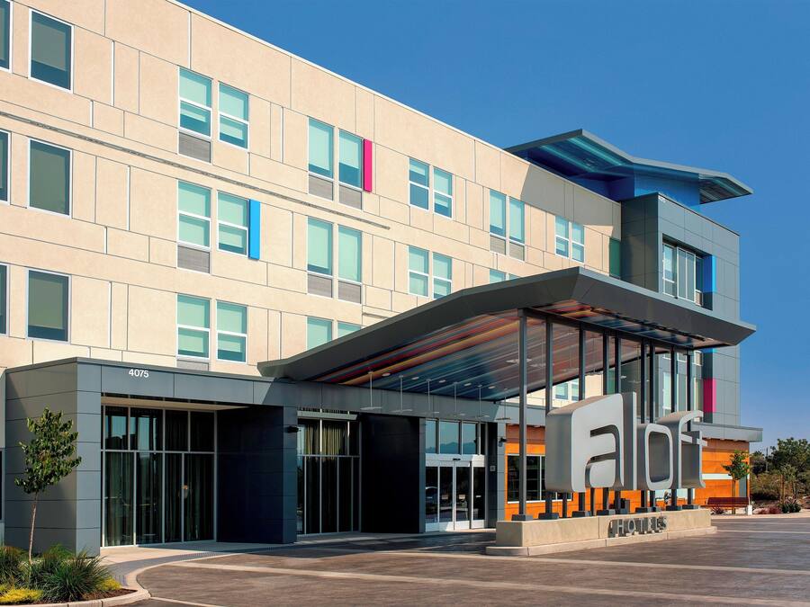 A modern hotel with a glass entrance, a flat roof, and a sign indicating it is a hotel.