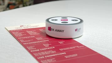 A white cylindrical device labeled "ASK AWAY" on a white surface with a red informational card beside it.
