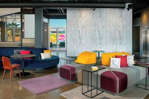 A modern lounge area with seating, tables, and a patterned wall. - Aloft by Marriott Dublin-Pleasanton (Dublin)