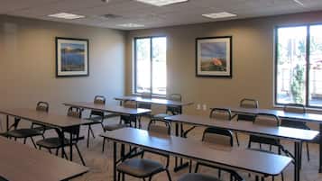 A conference room with multiple tables and chairs, large windows, and framed pictures on the walls.