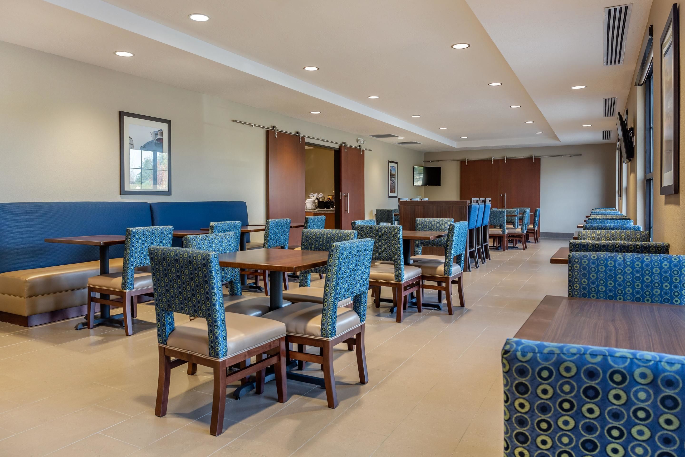 A hotel dining area with booths and tables, a reception desk, and a large window.