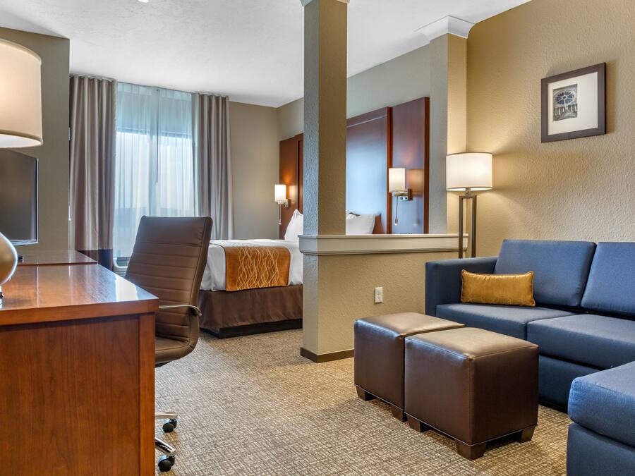 Ein Hotelzimmer mit Bett, Schreibtisch, Sessel, Sofa und Couchtisch.