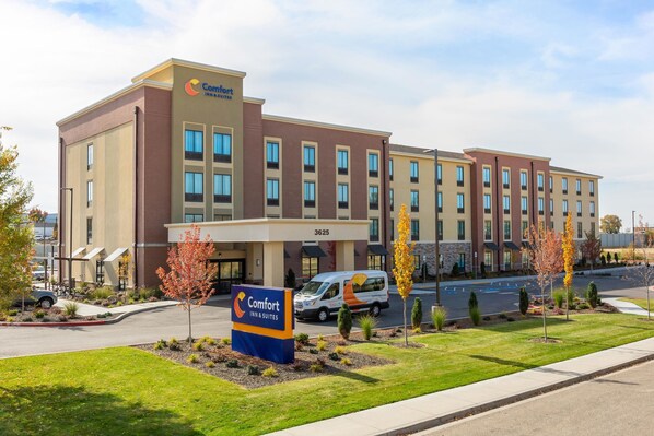 A Comfort Inn & Suites hotel with a modern design, featuring a large parking lot and a well-maintained lawn.